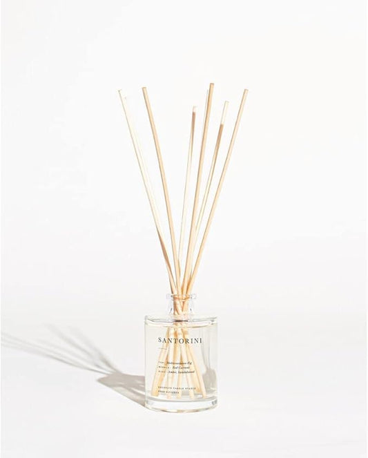 Diffuser bottle and reeds showcased on a white surface, emphasizing the 'Santorini' fragrance.