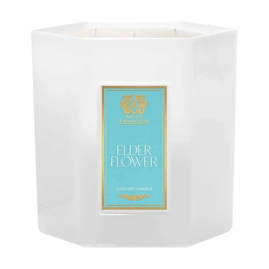 Clear glass jar candle with three wicks and an 'Elderflower' scent label visible.