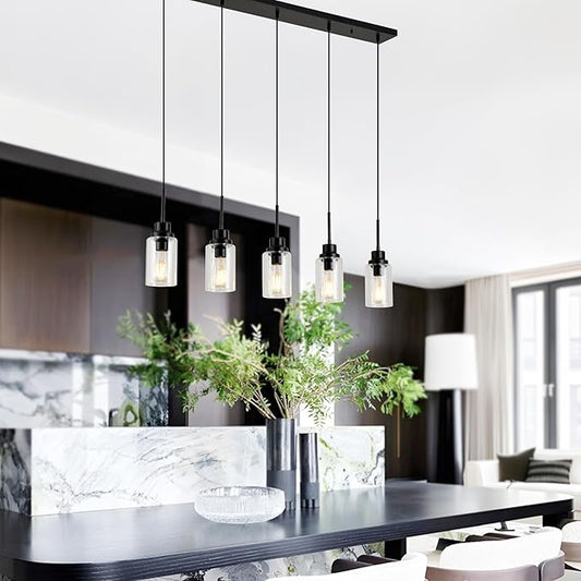 Close-up of one clear glass shade and the black metal fixture of the pendant light.