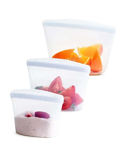 Three clear Stasher bags of varying sizes, arranged on a bright kitchen countertop.