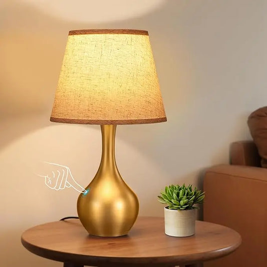 Close-up of the gold table lamp, showcasing its elegant design and touch-activated base.
