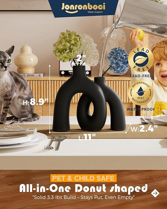 Close-up of the two matte black ceramic vases, showcasing the smooth, minimalist texture and hollow center.