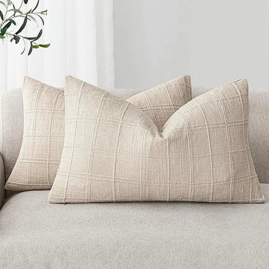 Close-up of the textured linen fabric with a subtle check pattern on a natural beige pillow cover.