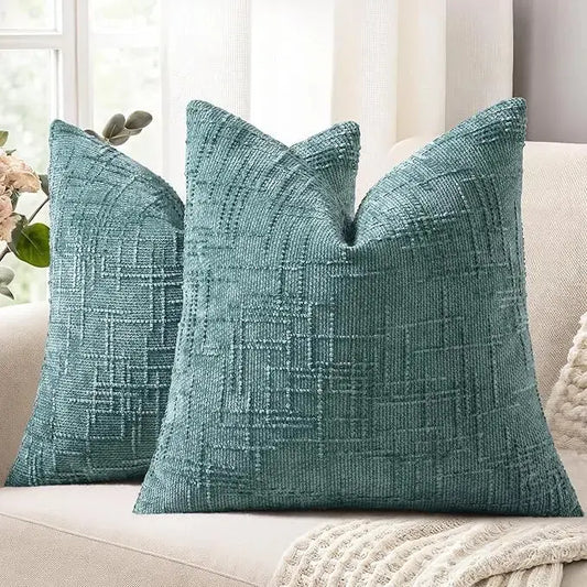 Two teal chenille throw pillow covers displayed on a light gray sofa in a modern living room.