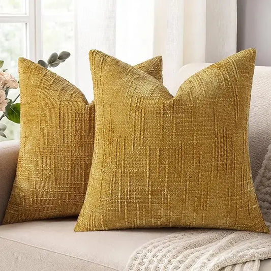 A pair of mustard yellow chenille throw pillow covers, 16x16 inches, with a thick textured slubby finish, on a couch.
