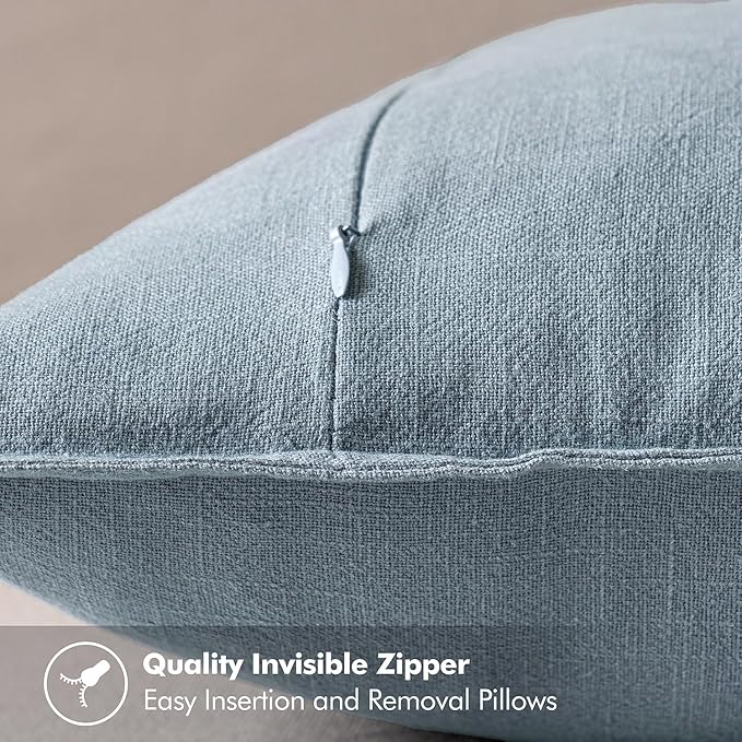 The soft, durable linen material of a blue grey pillow cover, shown with a gentle touch.