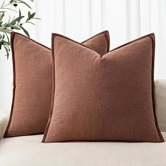 A pair of rust red linen throw pillow covers displayed neatly on a modern sofa.
