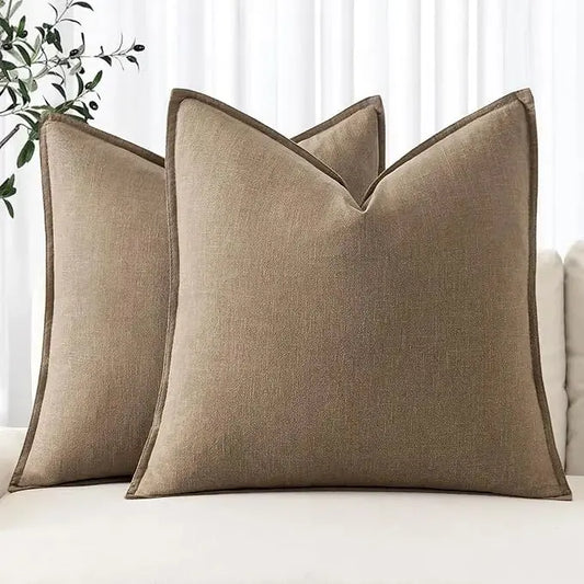 Two khaki linen throw pillow covers with a textured boho farmhouse design, displayed on a comfortable sofa.
