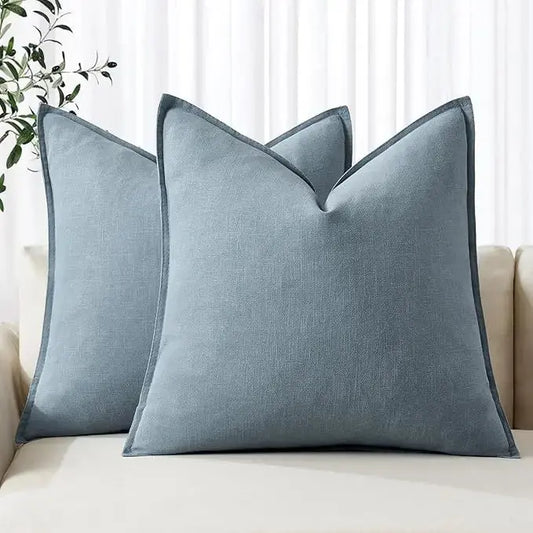 A pair of blue grey linen throw pillow covers displayed neatly on a modern sofa.