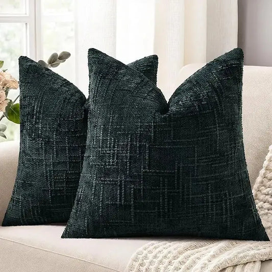 Pair of black chenille slubby throw pillow covers, 22x22 inch, arranged on a modern sofa.