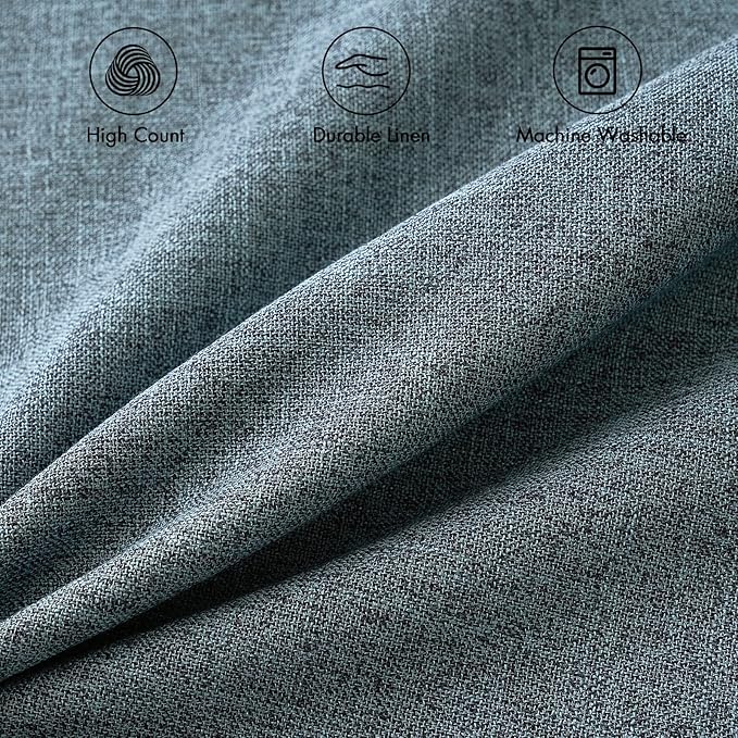 Two dusty blue farmhouse-style pillow covers arranged neatly on a light-colored sofa in a living room.