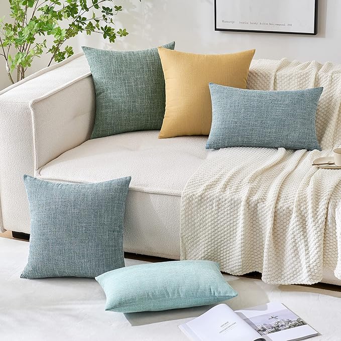 Decorative sage green accent pillow covers on a bed in a tranquil bedroom scene.