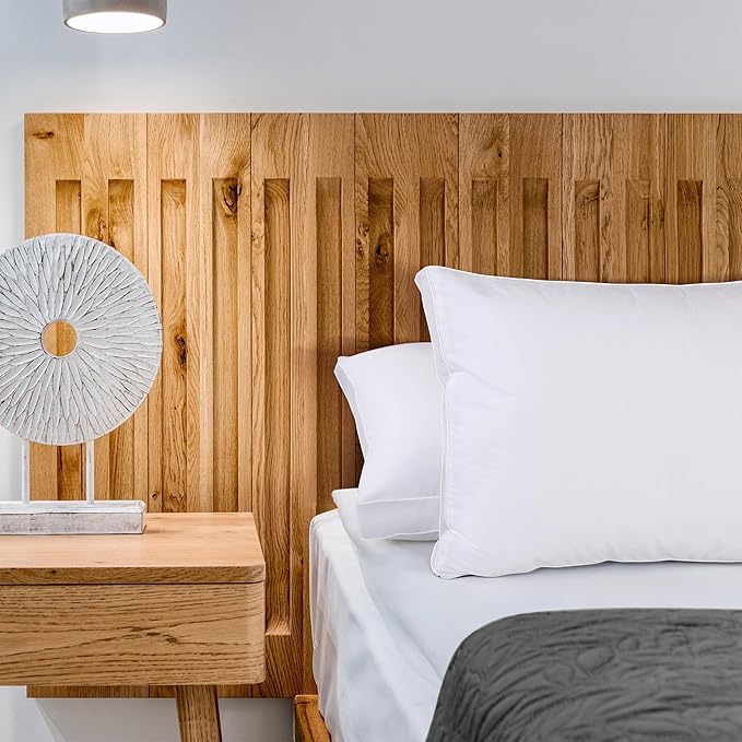 A hand gently pressing into a white bed pillow, demonstrating its responsive comfort and support.